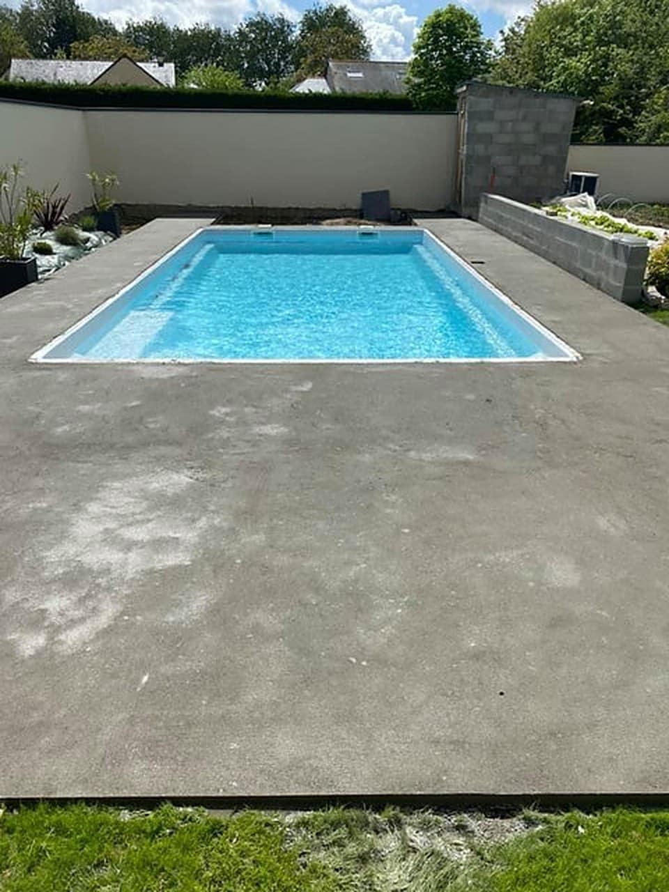 Avant : dalle béton brute autour de la piscine